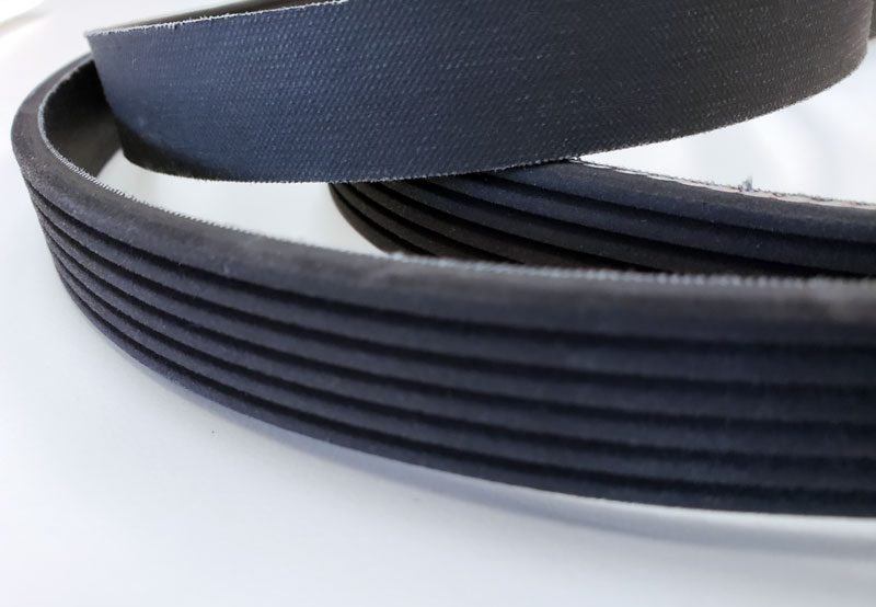 Close-up of black rubber belts with grooves on a white background.