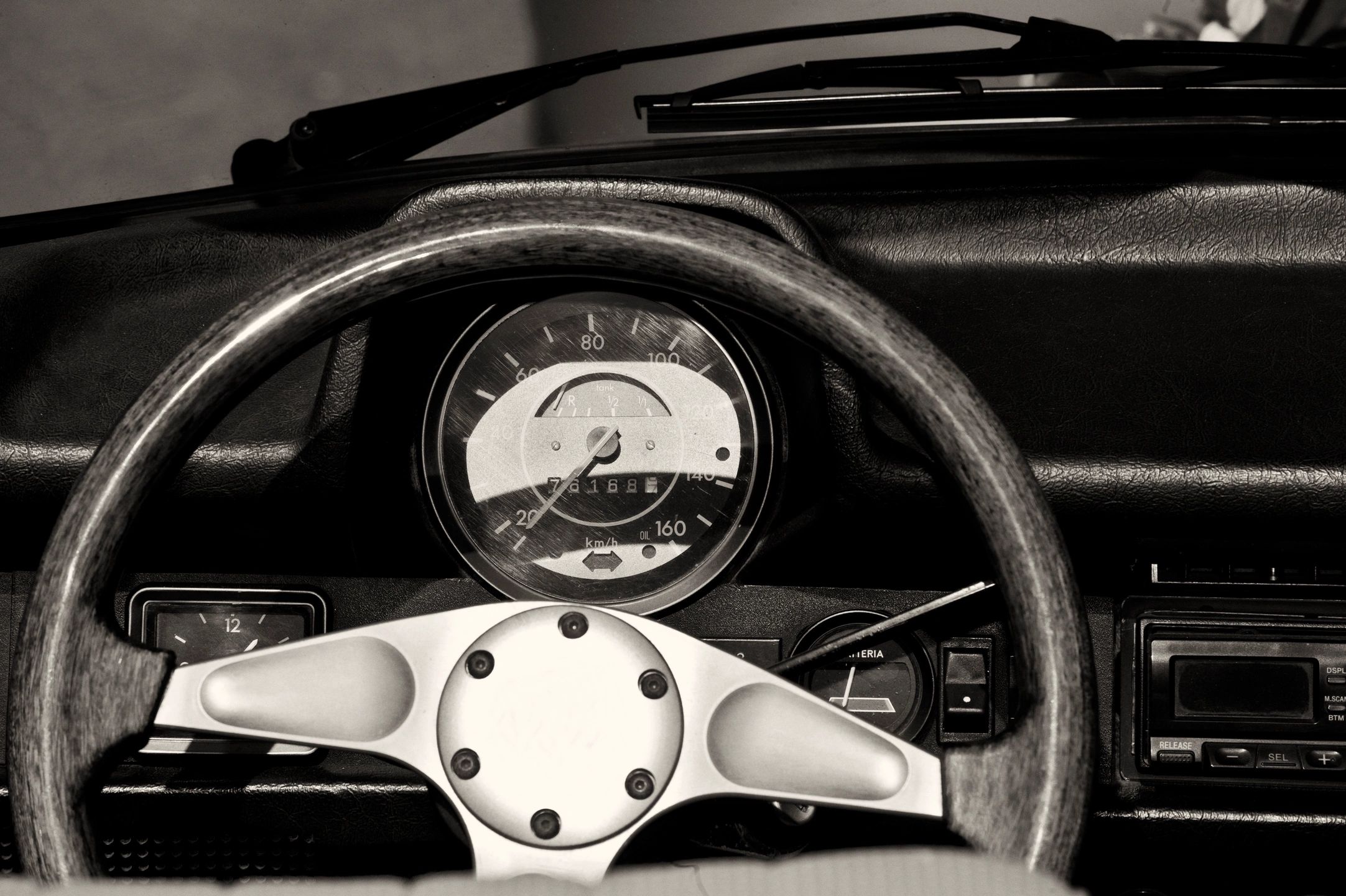 Close-up of a vintage car steering wheel and speedometer.