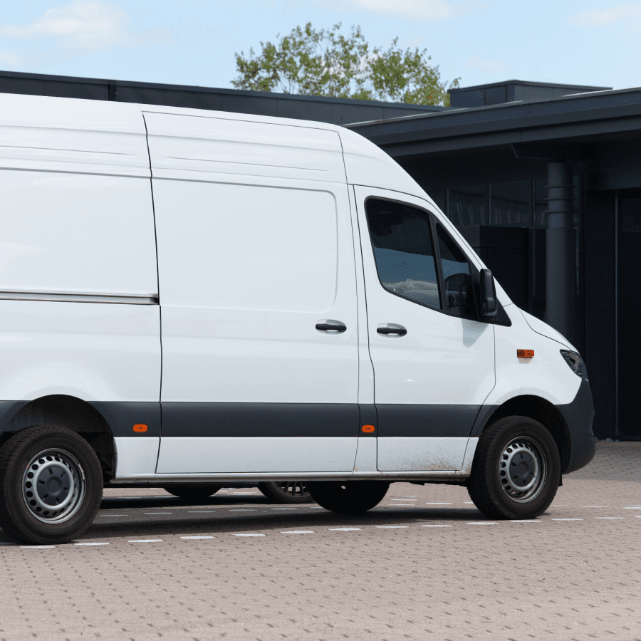 White cargo van parked on a paved area near a building.