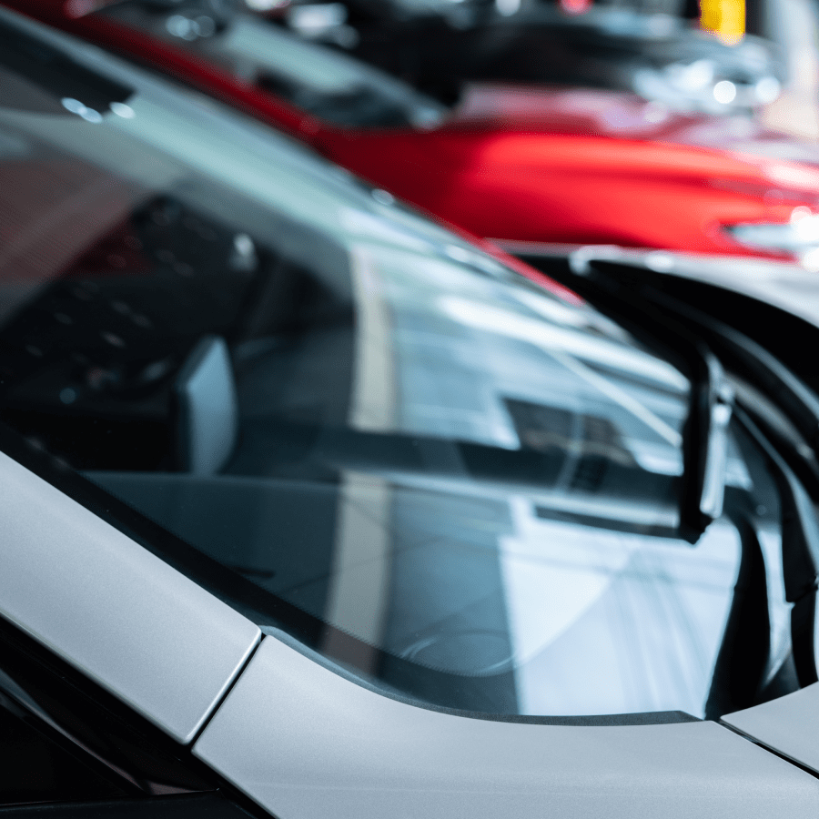 Close-up of cars parked in a row at a dealership or showroom.