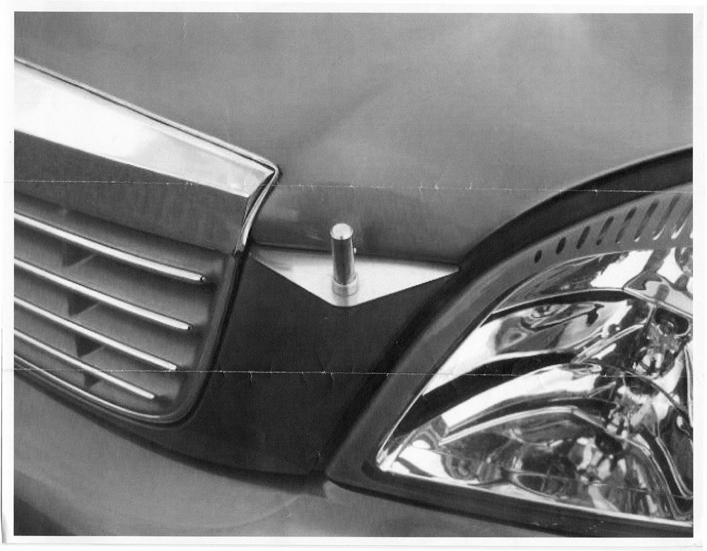 Close-up of a car's front grille and headlight in black and white.
