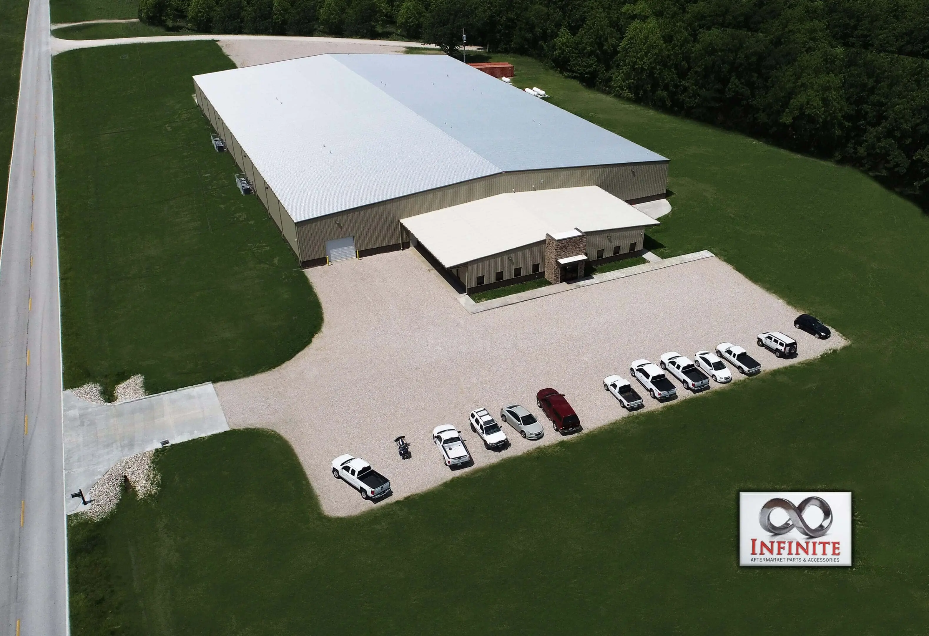 Aerial view of a large industrial building with parking lot and vehicles.